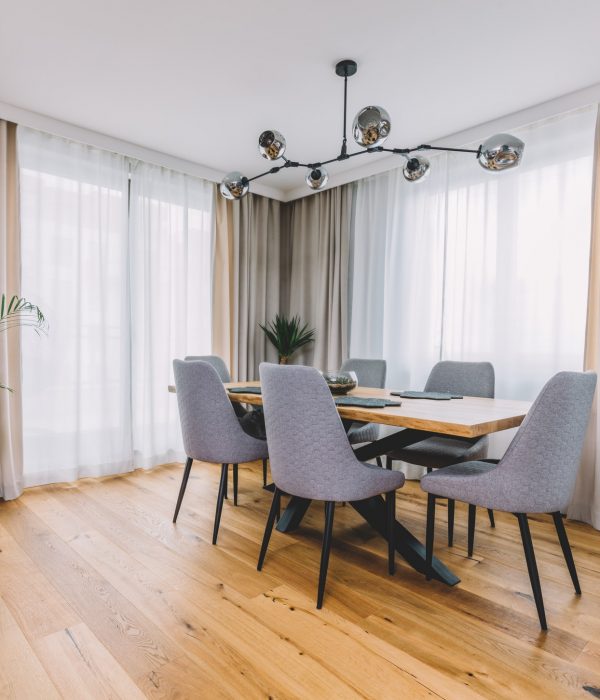 Dining room with wooden table and floor in modern apartment.