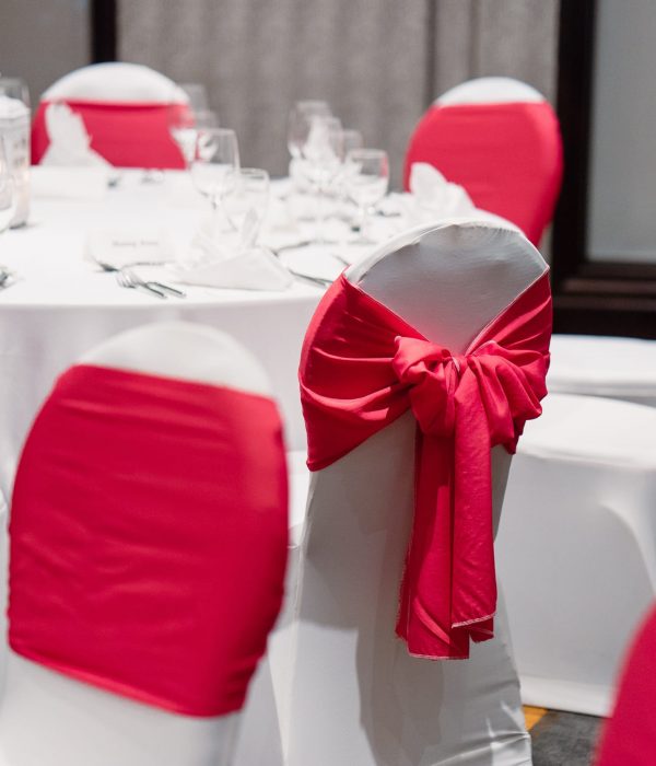wedding-reception-dinner-table-setup-in-white-and-red-theme-spandex-white-cover-chairs-with-red-sash_t20_8lvroJ